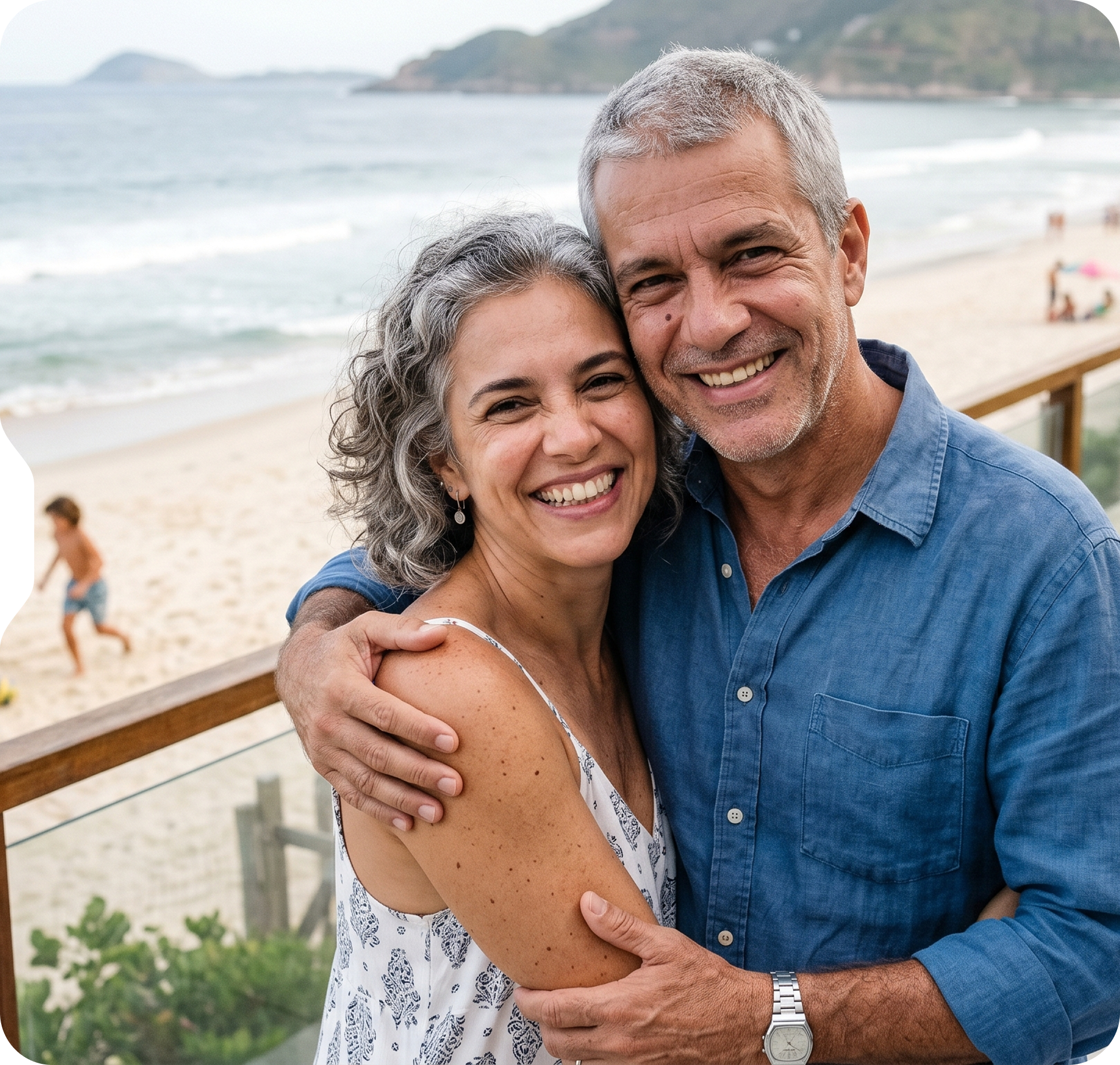 Casal sorridente em um dia ensolarado na praia, com o oceano ao fundo.