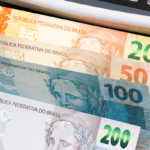 Notas de Real em máquina de contagem, com destaque para R$200, R$100, R$50 e R$20.