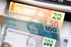 Notas de Real em máquina de contagem, com destaque para R$200, R$100, R$50 e R$20.